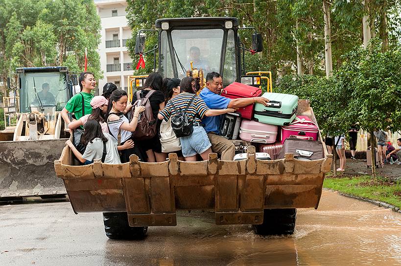Гуйлинь, Китай. Студенты едут на погрузчике по затопленной от паводка территории колледжа