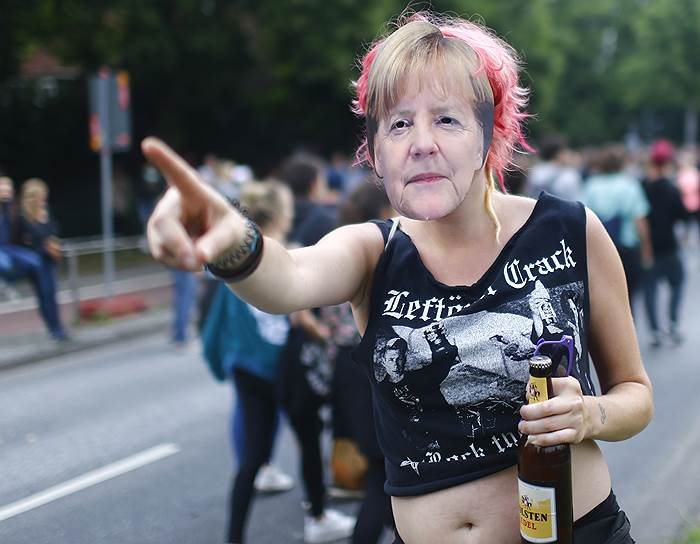 Активистка в маске канцлера Германии Ангелы Меркель на протестной акции