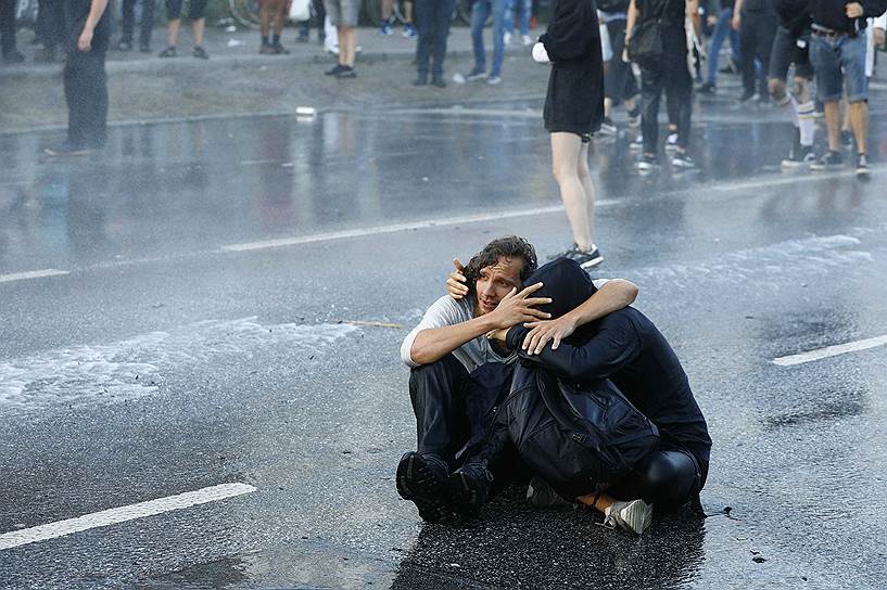 Протестующие, укрывающиеся от водометов, которые применили полицейские для разгона демонстрации