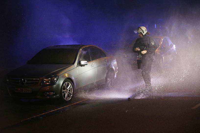 Полицейский осмотрел автомобиль, сгоревший во время демонстраций противников G20
