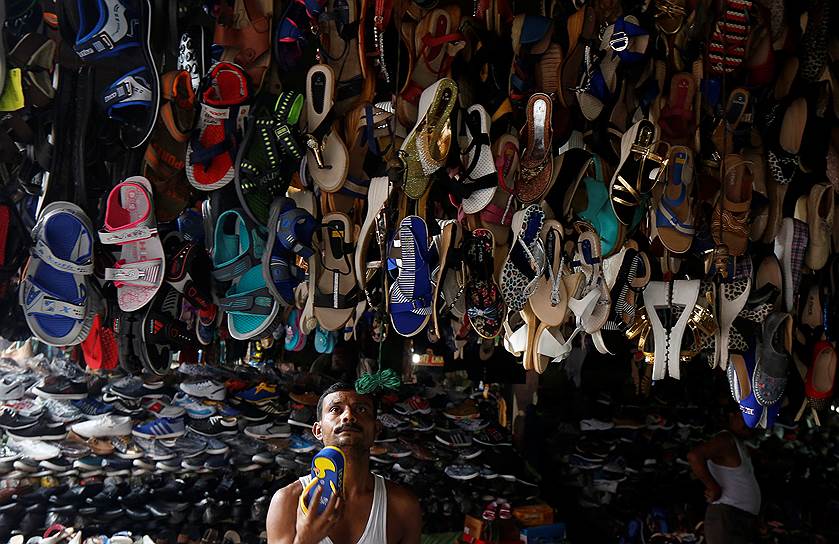 Калькутта, Индия. Лавочник вешает обувь на витрину 