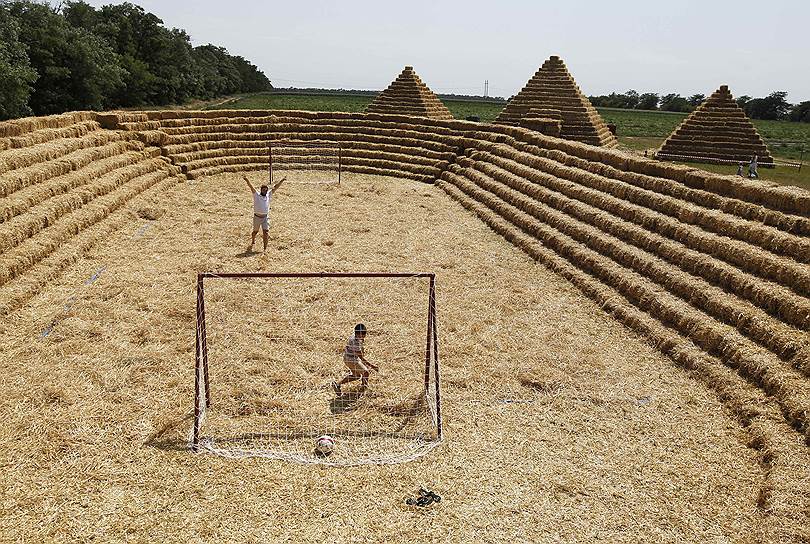 Село Красное, Россия. Люди играют в футбол на стадионе парка аттракционов построенных из соломы 