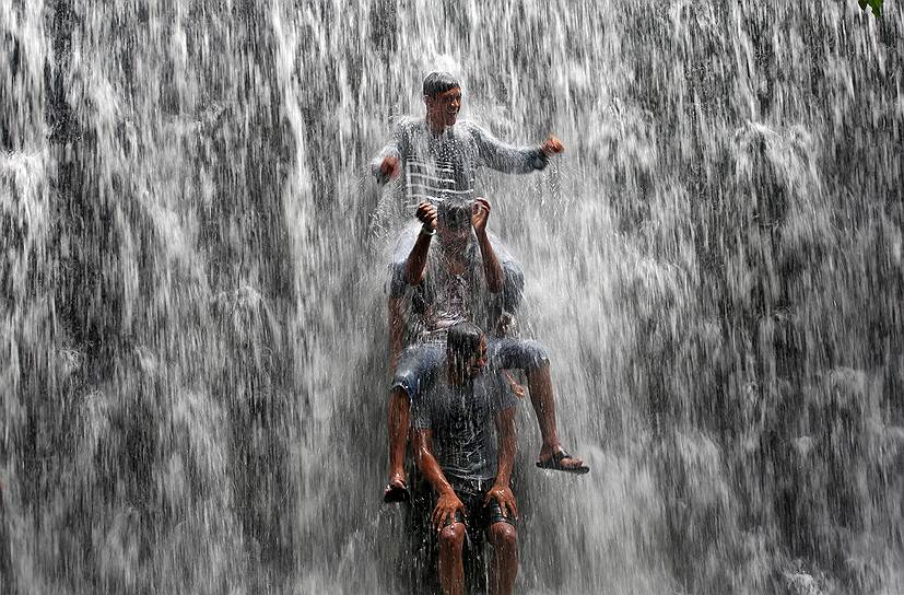 Мумбаи, Индия. Мальчики играются в водопаде, вызванном сильными ливнями