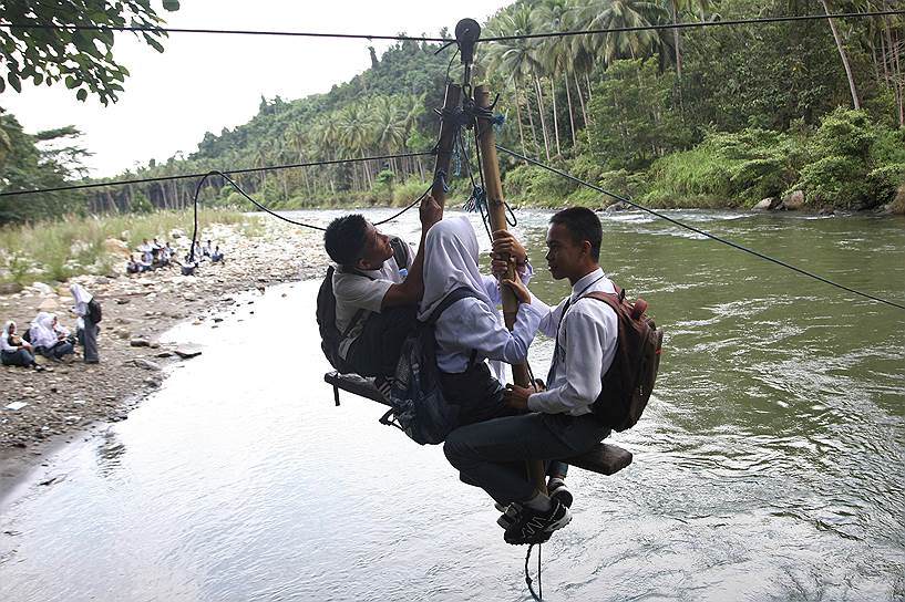 Колака Утара, Индонезия. Школьники перебираются реку по дороге домой 