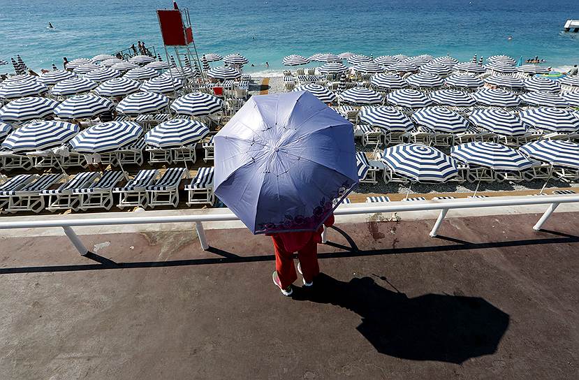 Ницца, Франция. Туристка гуляет под зонтом по набережной