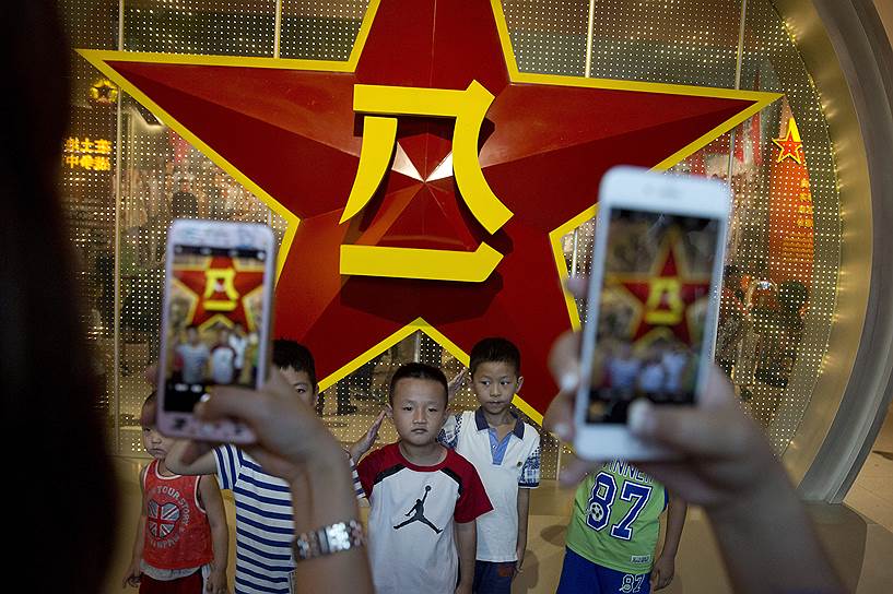 Пекин, Китай. Дети позируют на фоне эмблемы армии страны