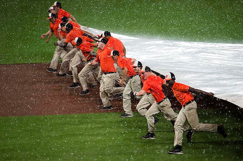 Балтимор, США. Обслуживающий персонал площадки натягивает брезент над полем из-за дождя в третьем тайме игры между командами Kansas City Royals и Baltimore Orioles в парке Oriole 