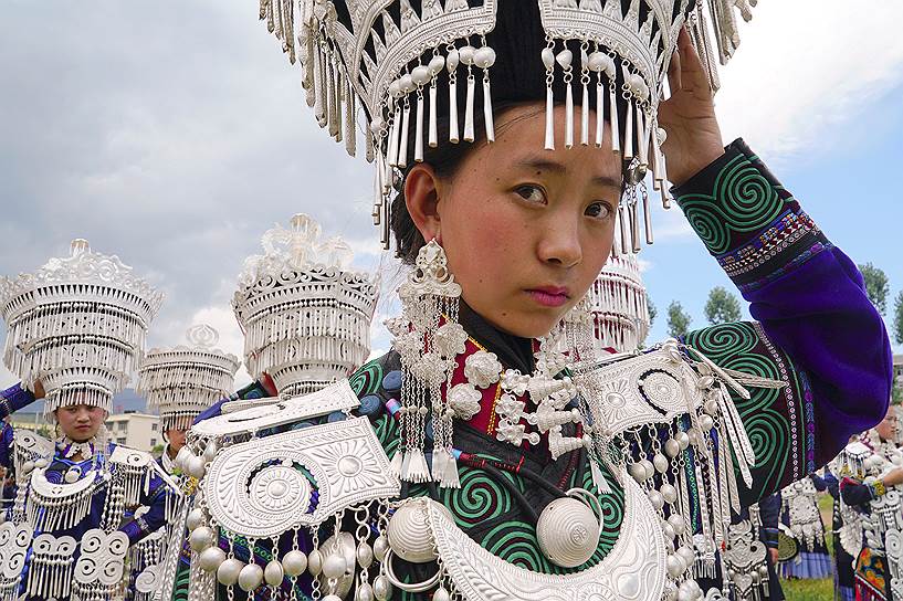Бутуо, Китай. Девушка, принадлежащая к этническому меньшинству Ий, ждет начала представления в честь Фестиваля факелов