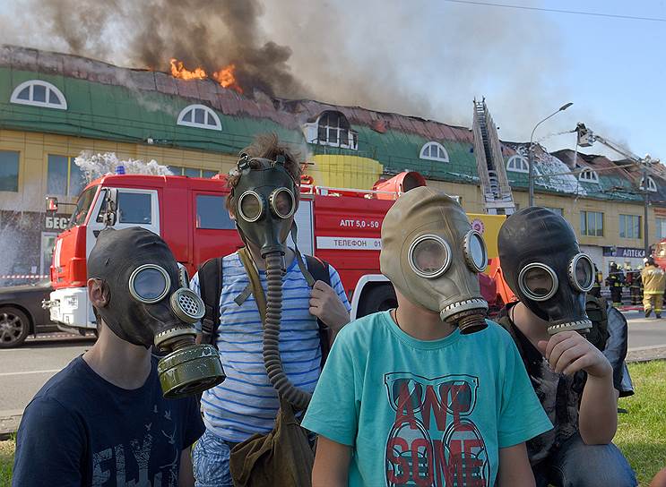 Москва, Россия. Дети в противогазах возле горящего здания торгового центра «Атом» на Таганской площади