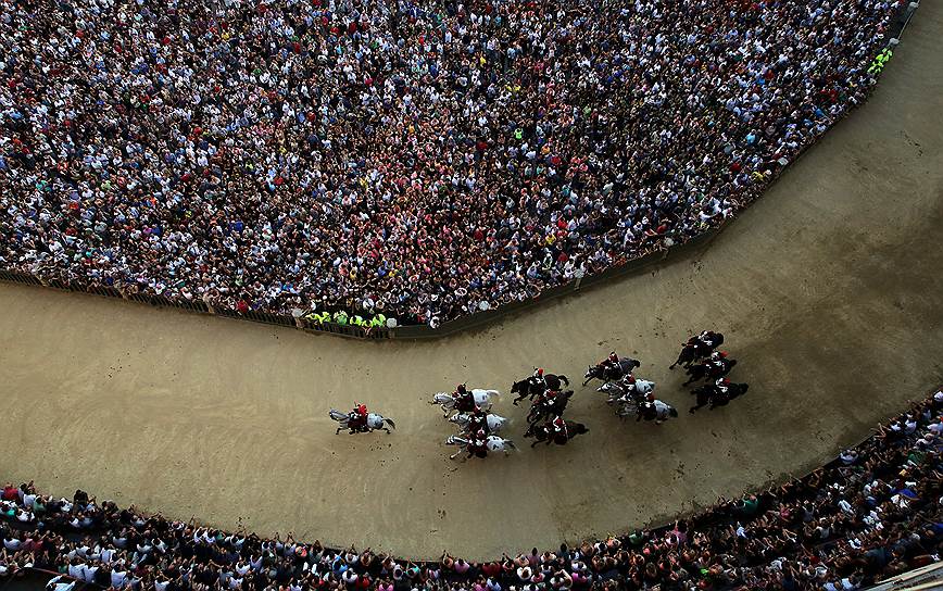 Сиена, Италия. Карабинеры едут на лошадях во время парада перед началом пятых традиционных скачек, известных как Палио