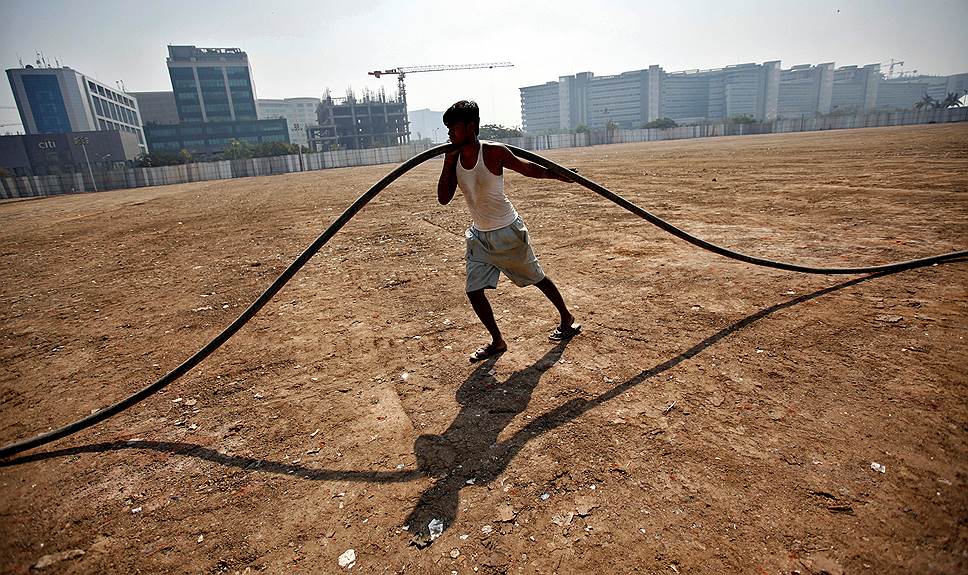 Мумбаи, Индия. Рабочий  тянет подземный кабель на строительной площадке коммерческого комплекса