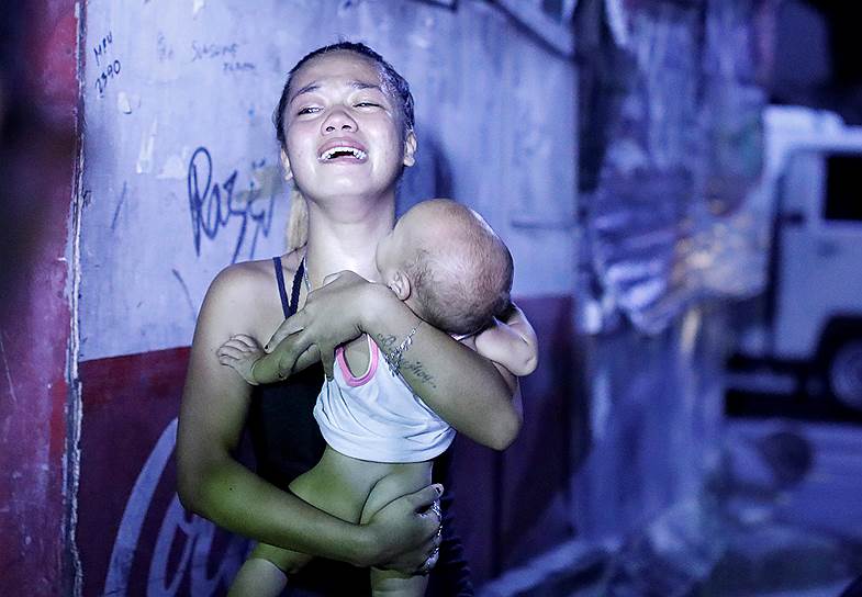 Манила, Филиппины. Плачущая женщина с ребенком на руках. Ее муж был убит во время антинаркотической операции