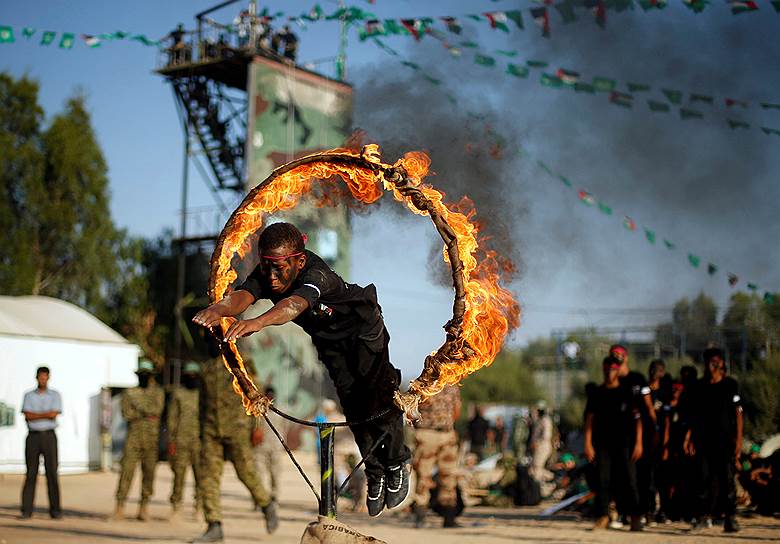 Хан-Юнис, Сектор Газа. Палестинец прыгает через огненное кольцо во время выпускной церемонии военных