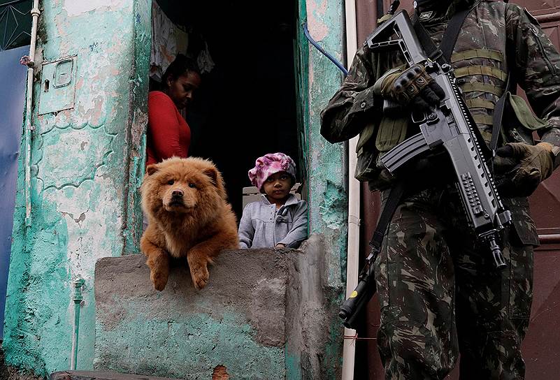Рио-де-Жанейро, Бразилия. Вооруженный член патруля и местные жители во время рейда против организованной преступности в одном из районов города