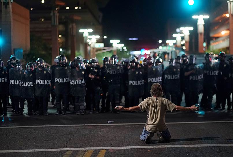 Аризона, США. Протестующий стоит на коленях перед полицейским кордоном
