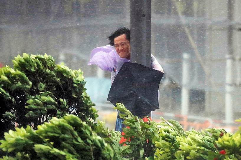 Гонконг, Китай. Мужчина держится за столб во время сильного ветра, вызванного тайфуном