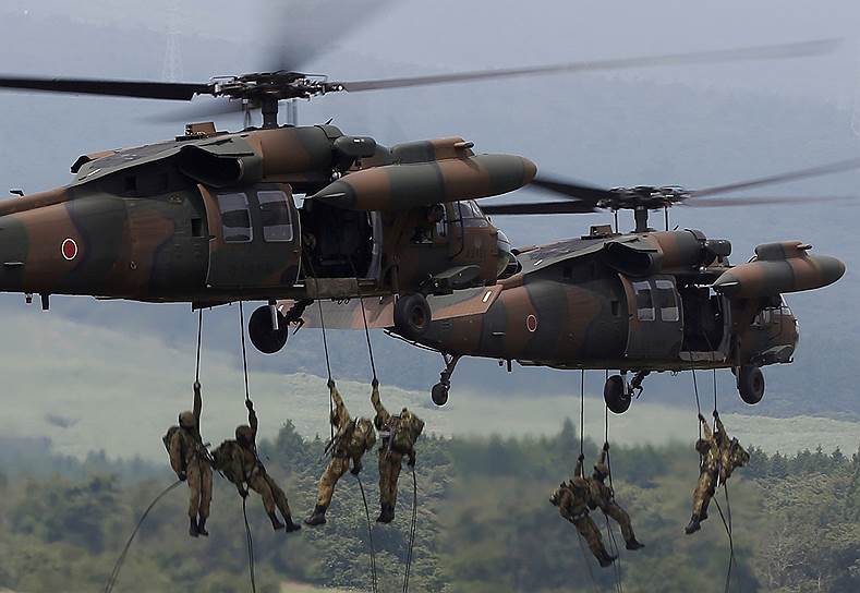 Токио, Япония. Солдаты сухопутных сил самообороны спускаются по веревке с вертолетов во время ежегодных учений около горы Фуджи