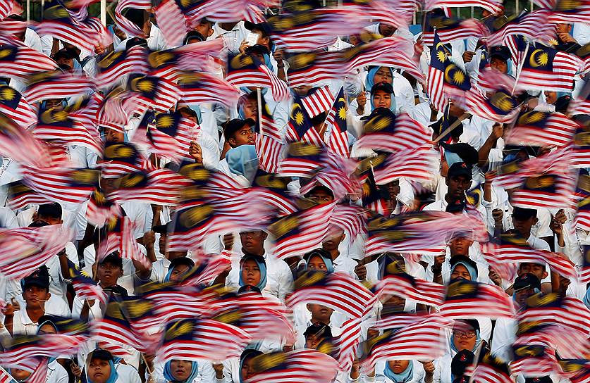 Куала-Лумпур, Малайзия. Люди держат в руках флаги страны во время празднования Дня независимости