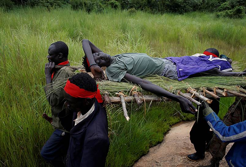Между Кайей и Йонду, Южный Судан. Участники Национально-освободительного оппозиционного движения несут на носилках раненого после столкновения с правительственными войсками повстанца