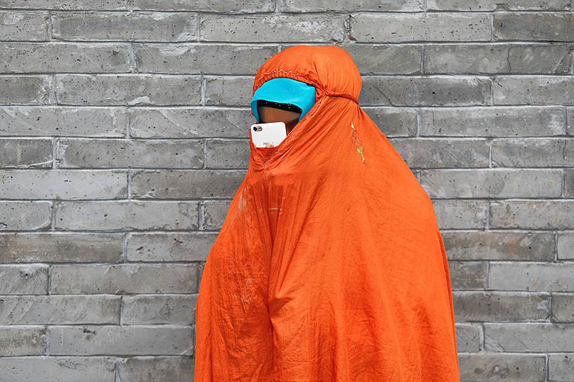 Пекин, Китай. Женщина в традиционном исламском облачении смотрит в смартфон