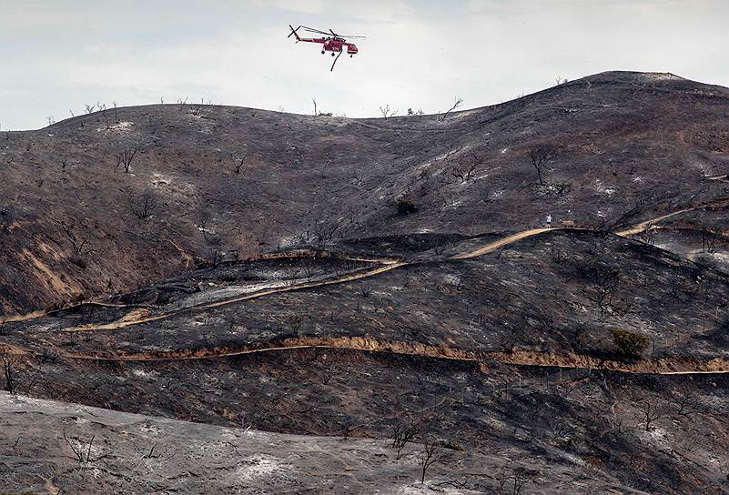 Бурбанк, Калифорния, США. Вертолет летит над выгоревшей в результате природных пожаров местностью
