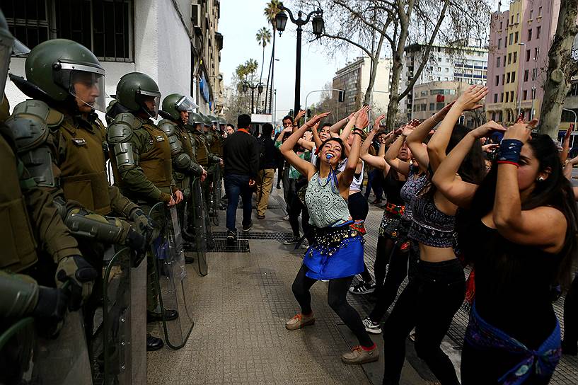 Сантьяго, Чили. Протестующие танцуют перед полицейскими во время студенческого марша в поддержку реформы образовательной системы