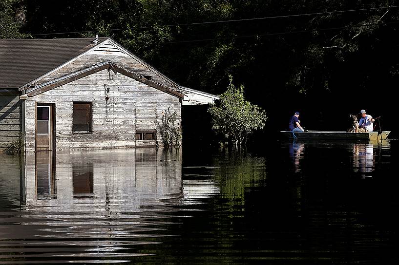 Вайдор, США. Лодка с пассажирами проезжает мимо ушедшего под воду в результате урагана «Харви» дома 