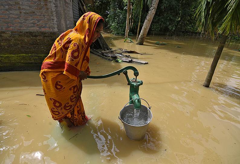 Округ Сонитпур, Индия. Женщина набирает воду в частично затопленной колонке