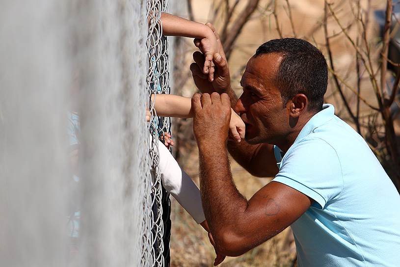 Коккинотримития, Кипр. Сирийский мигрант целует руку своего ребенка, прибывшего в лагерь беженцев под Никосией