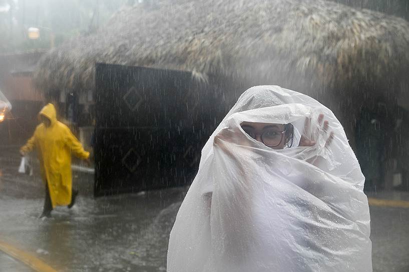 Побережье Баваро, Доминиканская Республика. Женщина накрыла себя пластиковым пакетом по пути на работу во время урагана «Мария»