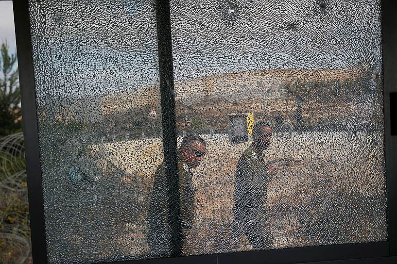Хар-Адар, Западный берег реки Иордан. Израильские солдаты за окном стеклянного стенда, поврежденного во время нападения палестинского боевика, убившего троих человек  