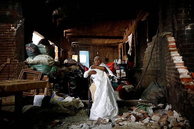 Сан Хуан Пилкайя, Мексика. 88-летняя местная жительница держит свое свадебное платье, за которым вернулась в дом во время землетрясения 