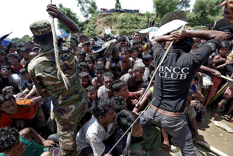 Кокс-Базар, Бангладеш. Военнослужащие и сотрудники местной службы безопасности сдерживают беженцев-рохинджа, которые стоят в очереди за помощью 