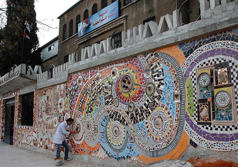 Сирийский художник делает мозаику из переработанных материалов на стене дамасской школы, 2011 год