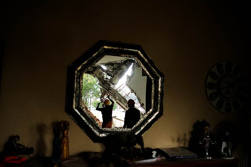 Мехико, Мексика. Отражение в зеркале рабочих, разбирающих завалы после землетрясения