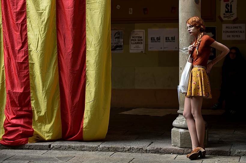 Барселона, Испания. Студентка стоит у флага Каталонии в здании университета