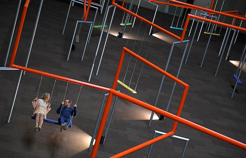 Лондон, Великобритания. Посетители галереи Тейт сидят на качелях, являющихся частью инсталляции датских художников из арт-группы Superflex