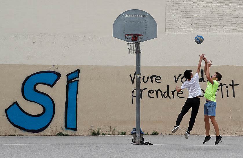 Барселона, Испания. Молодые люди играют в баскетбол на фоне граффити за независимость Каталонии 