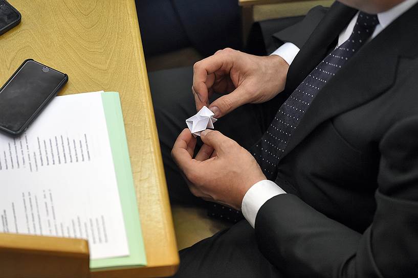 Депутат делает оригами из бумаги во время заседания