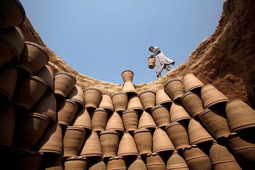 Пешавар, Пакистан. Мужчина складывает друг на друга глиняные горшки для обжига в печи