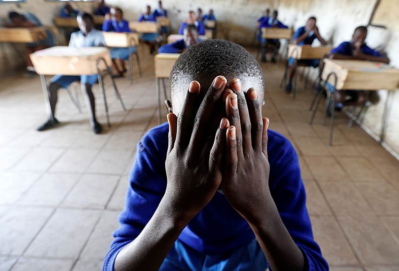 Найроби, Кения. Ученик начальной школы молится перед выпускным экзаменом 