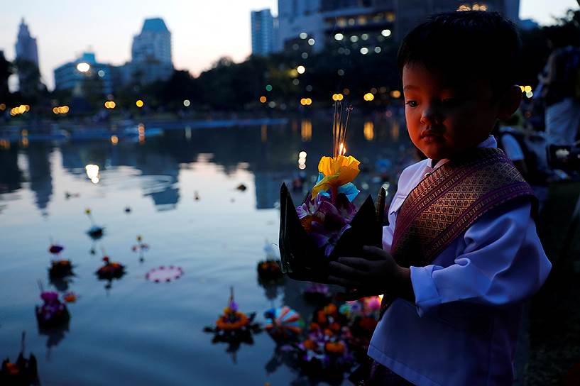 Бангкок, Таиланд. Мальчик в национальном костюме готовится запустить в водоем крохотный плотик со свечой (кратхонг) в честь лойкратхонга — ежегодного праздника символического перерождения тайцев