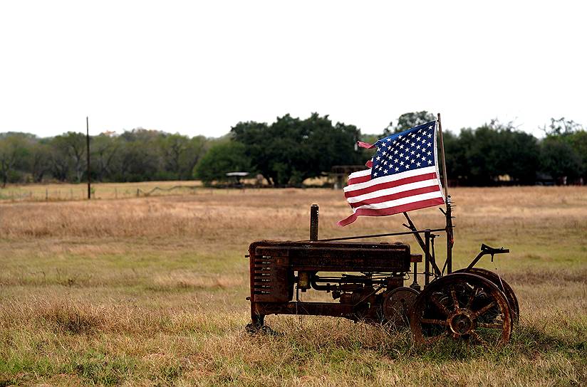Сазерленд-Спрингс, штат Техас (США). Старый трактор с американским флагом вблизи баптистской церкви, в которой произошла стрельба