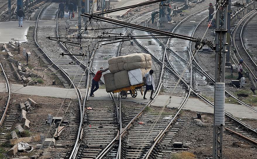 Нью-Дели, Индия. Двое мужчин перевозят вещи через железнодорожные пути
