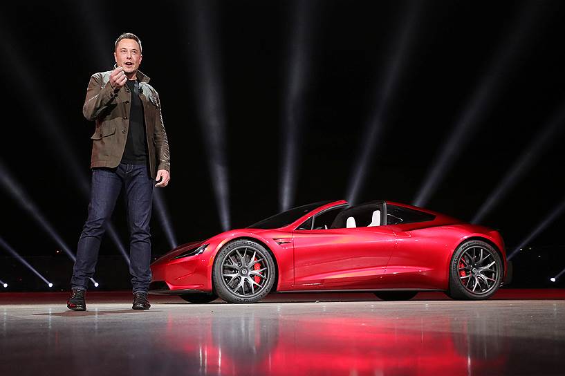 Создатель Tesla Илон Маск на фоне электроспорткара Roadster