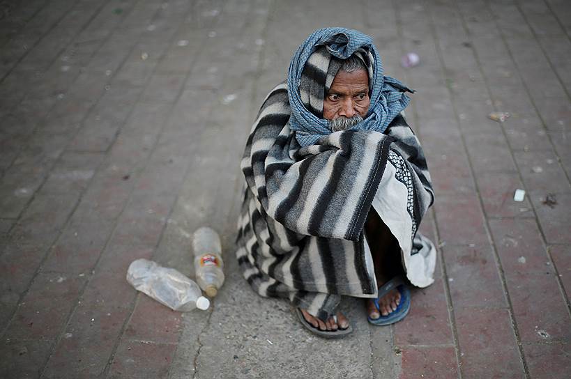 Нью-Дели, Индия. Бездомный мужчина завернулся в плед, чтобы согреться