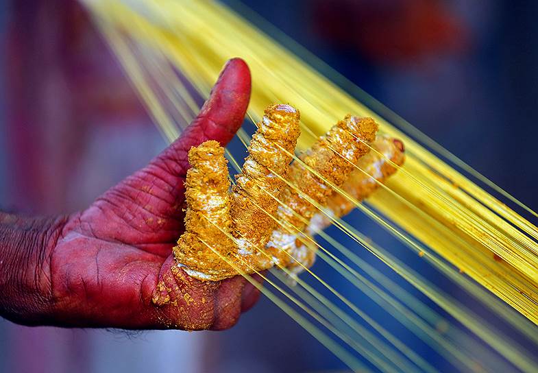 Ахмадабад, Индия. Рабочий раскрашивает нити, которые станут частью воздушных змеев