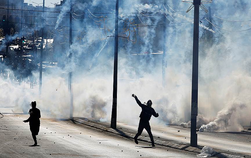 Вифлеем, Западный берег реки Иордан. Палестинец бросает камень в полицию, применившую против протестующих слезоточивый газ 
