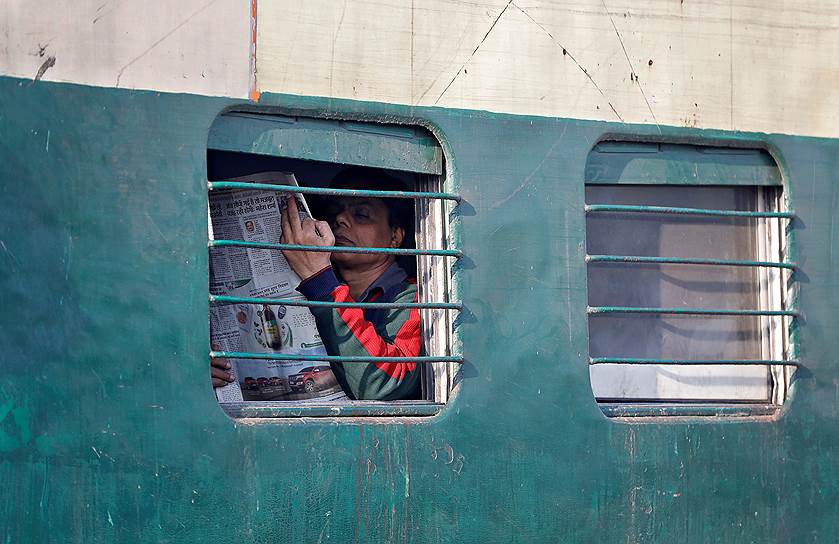 Нью-Дели, Индия. Местный житель читает газету в поезде