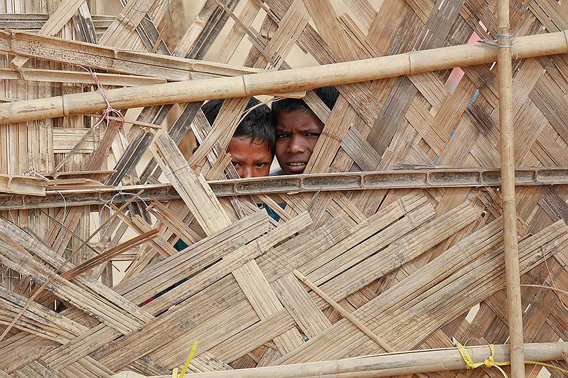 Кокс-Базар, Бангладеш. Беженец-рохинджа смотрит в дыру в заборе центра раздачи гуманитарной помощи